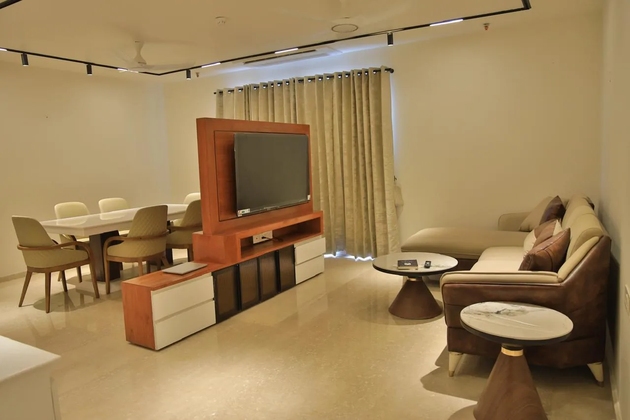A finished living and dining room by Shine Decor with track lights, a wooden TV partition, and a six-seater dining table.